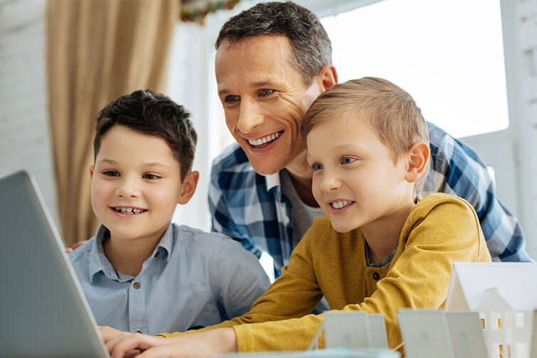 Dad and children smiling whilst using a laptop together