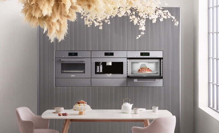 Bank of three Miele ovens in a sunny modern kitchen