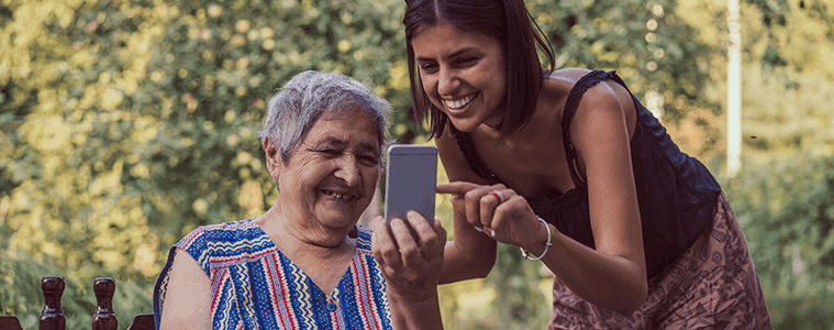 Two women smiling as they use a smartphone together