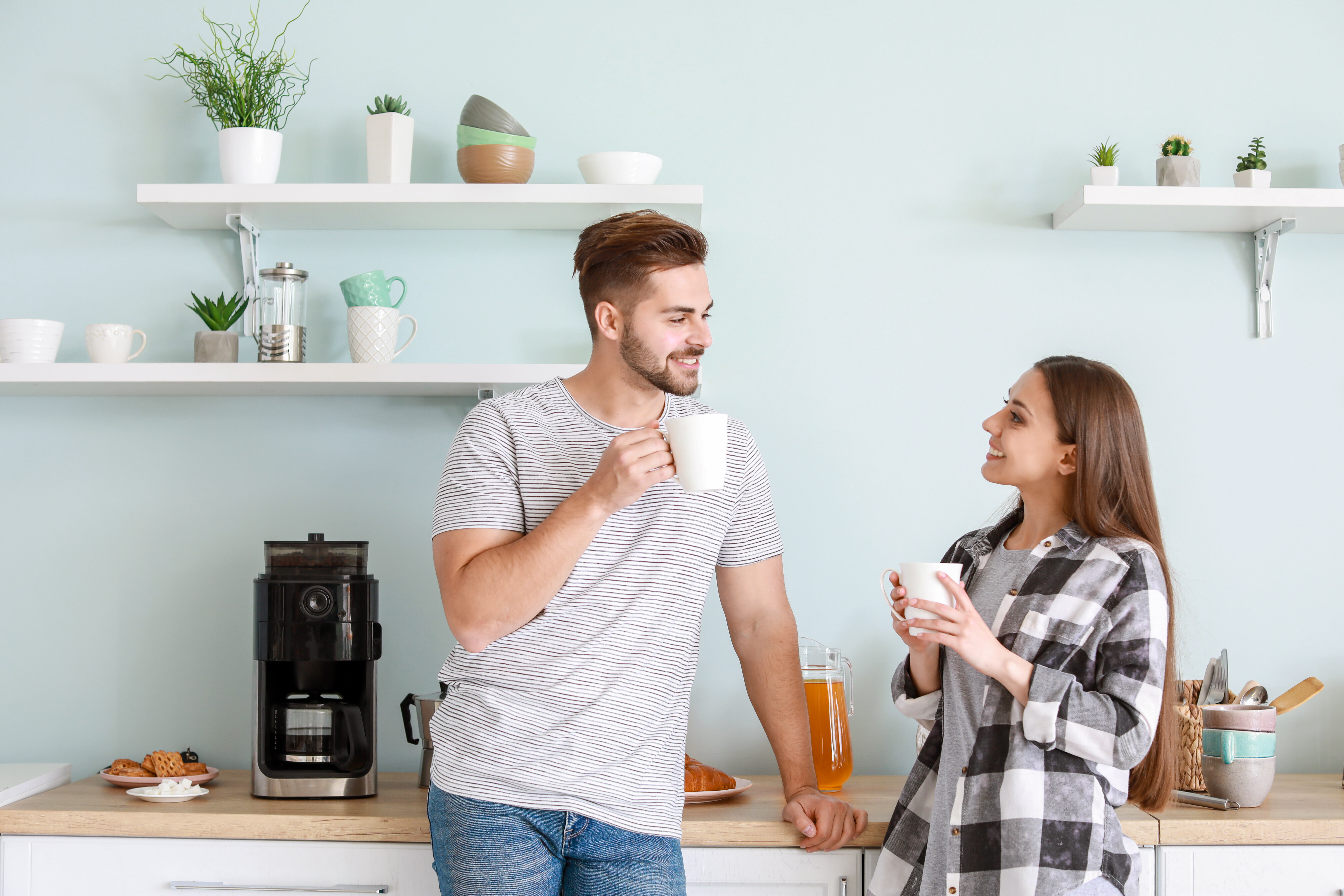 Happy couple enjoying a hot coffee in their kitchen