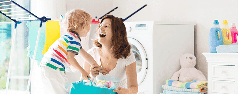 A mother and her young son organise washing together in the laundry.