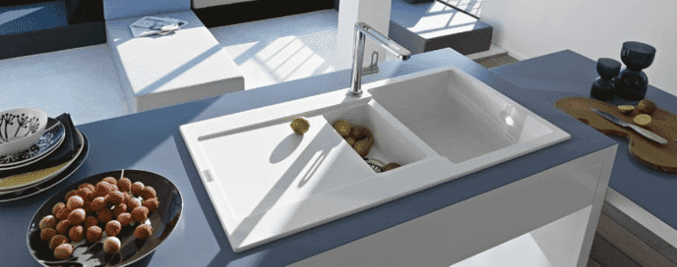 A white sink in a kitchen with blue benchtops.