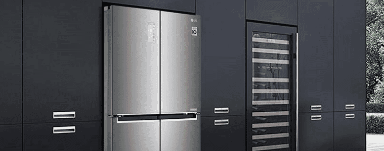 A chrome fridge sits with sleek black industrial cabinets.