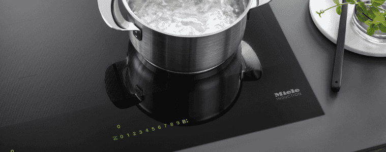 A pot of water boils on a Miele induction cooktop.