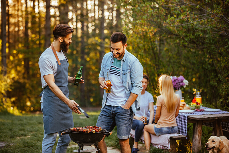 Men using portable BBQ for a picnic outside. 