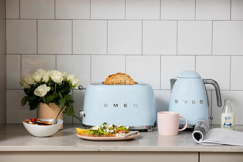 Pastel blue Smeg toaster and kettle on bench with breakfast