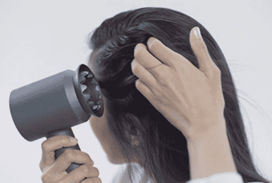 Woman using dyson supersonic to dry her straight hair