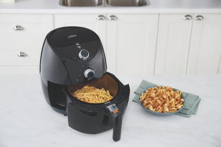 A Sunbeam air fryer and delicious snacks on a benchtop in a modern ktichen