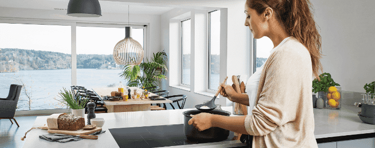 A woman preparing a meal on an induction cooktop in a beautiful modern home. 