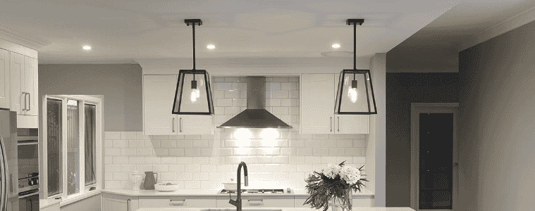 Two black pendant lights in a white Hamptons style kitchen.