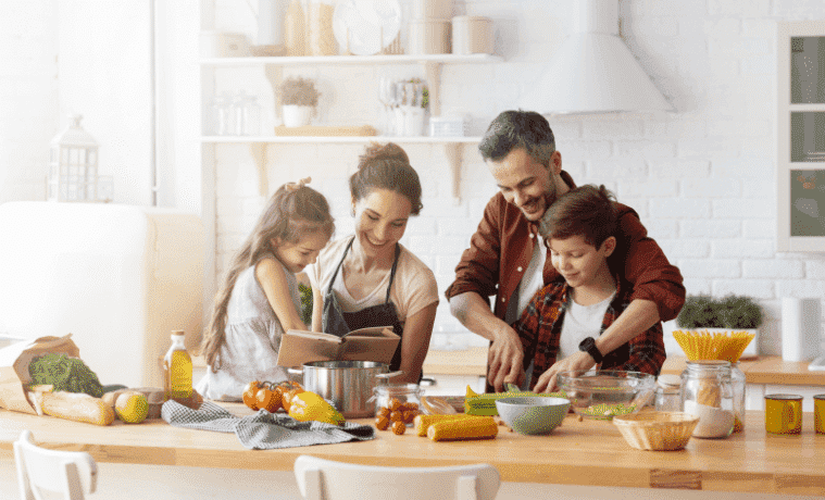 Happy family of four preparing a meal in their clean modern kitchen