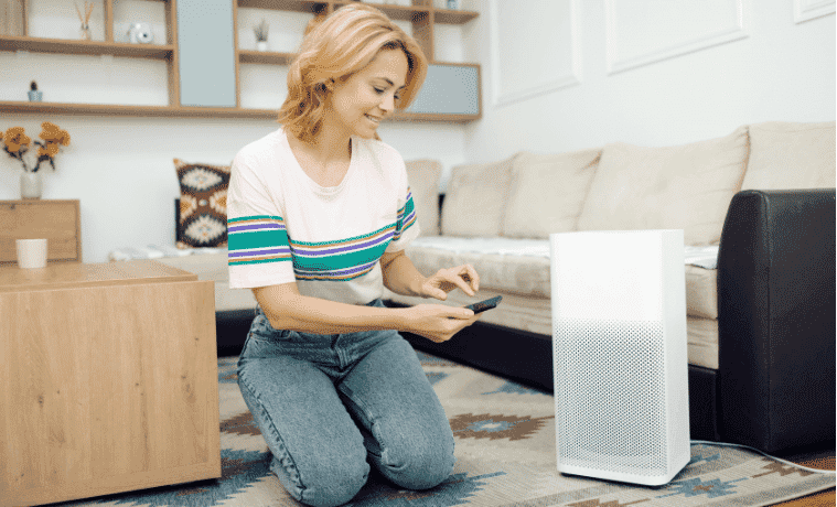 A woman adjusts the settings on her air purifier through an app on her smart phone.