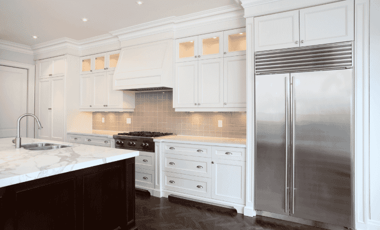 A classically styled white kitchen with silver appliances.