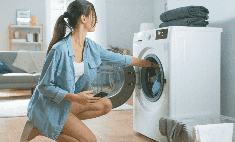 A woman puts laundry in her dryer.