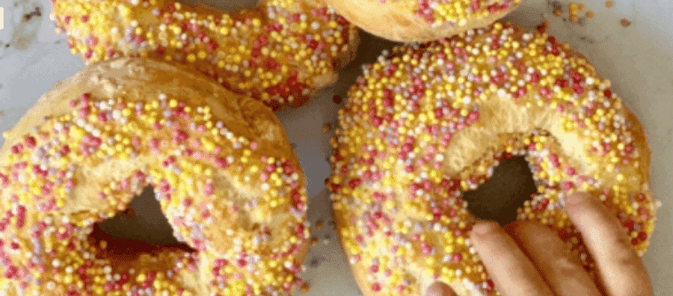 Hand grabbing a fairy bread bagel from a plate