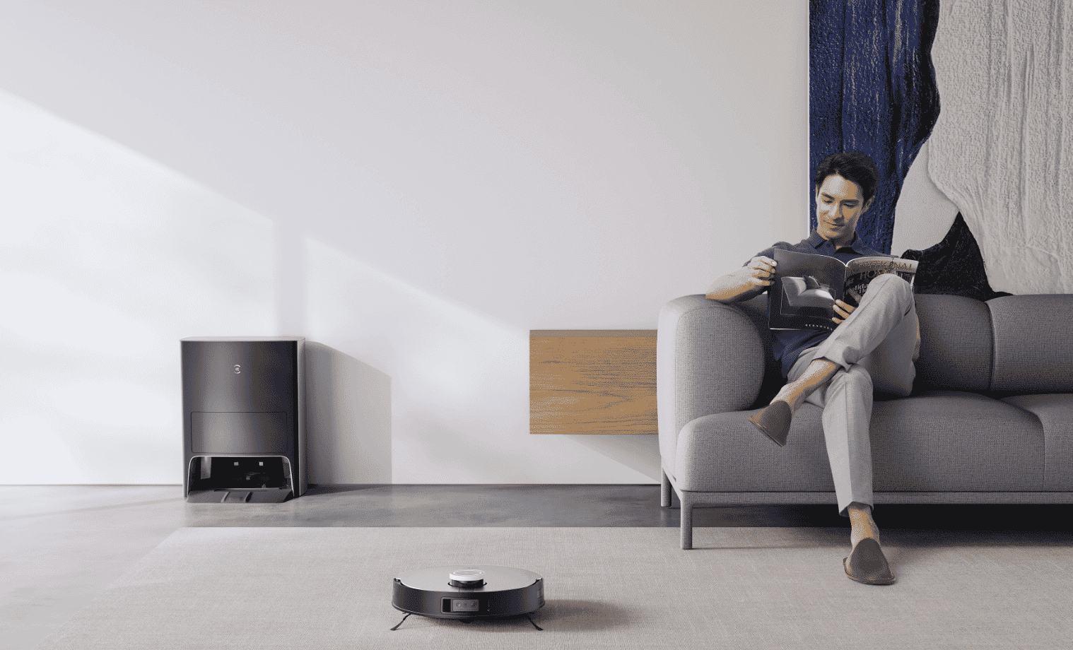 Man sitting on his couch whilst his ECOVACS DEEBOT X1 OMNI cleans. 