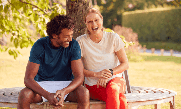 A man and woman in fitness clothing rest on a bench.