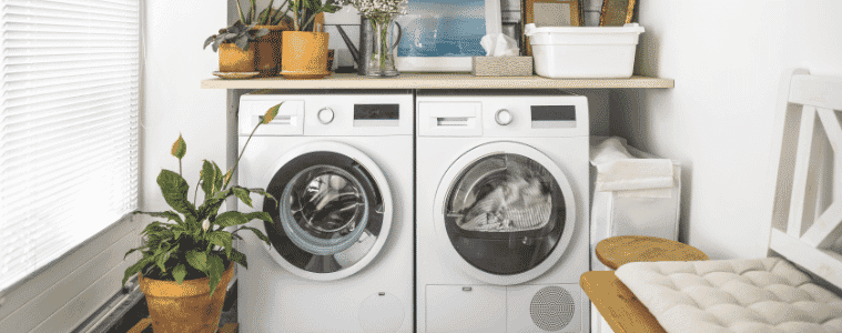 A washing machine and dryer sit side-by-side in a small laundry.