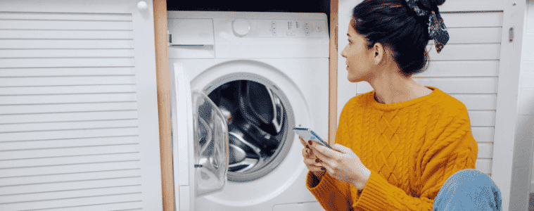 A woman uses her smartphone to control her washing machine.