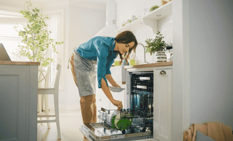 A woman loads the dishwasher in her kitchen.