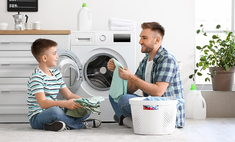 A son helps his father unload and fold the laundry.