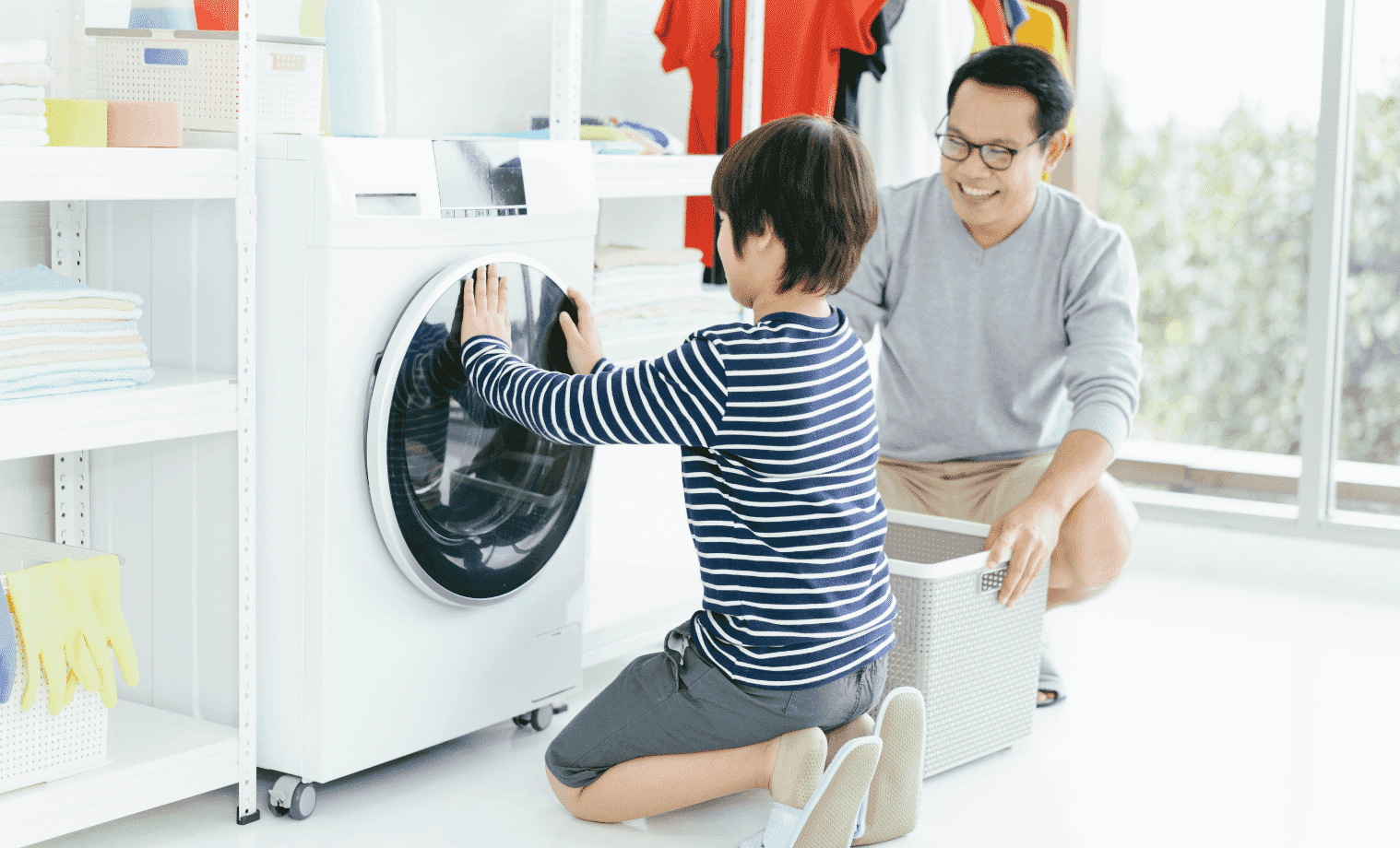 A father and son load clothes into a washing machine