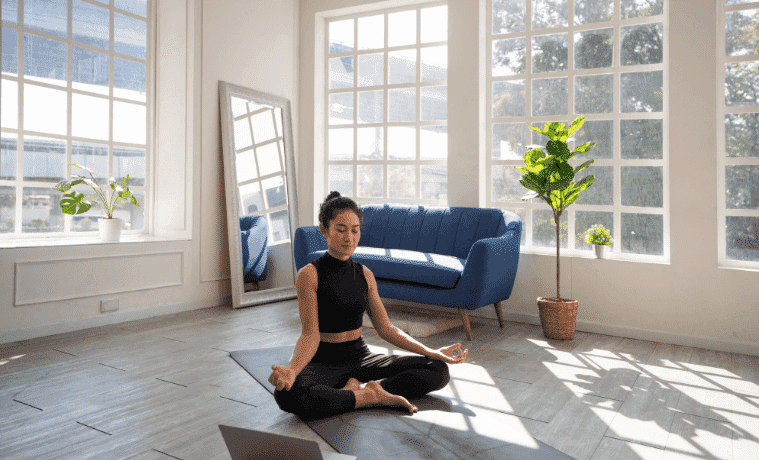 A woman meditates in her home.