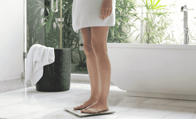 Woman in bathroom standing on digital weight scale