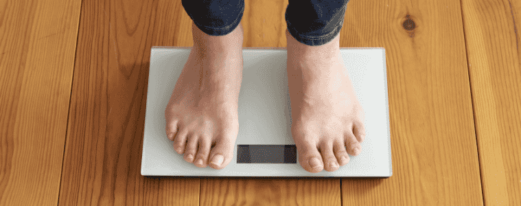 Woman's feet on scales, sitting on a wooden floor