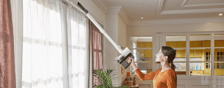 A lady vacuuming her curtain using the LG handstick vacuum