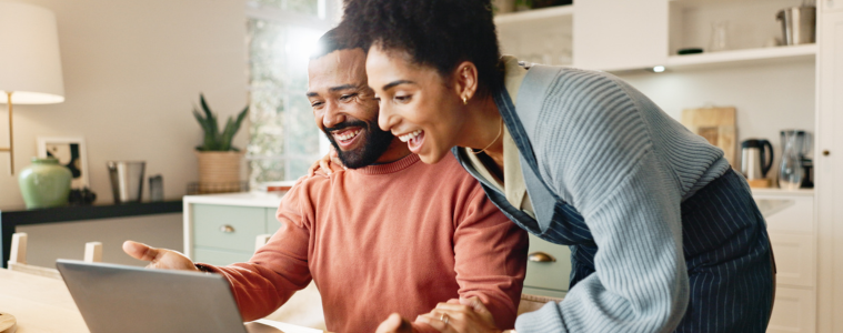 Happy couple looking at laptop at home