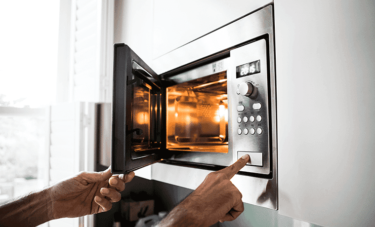 A person presses the button to open their microwave.