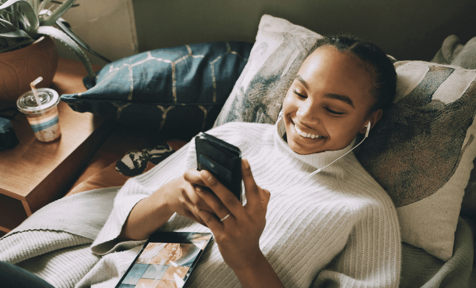 A teenage girl uses her mobile device while in bed at home