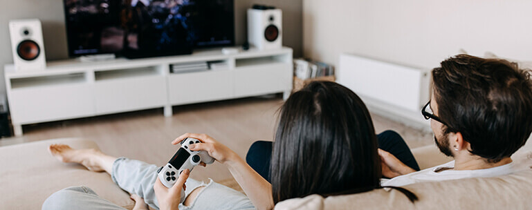 A man and woman play games together on the couch.