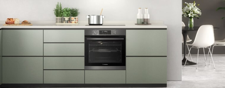 A built-in oven in a small sage green kitchen.