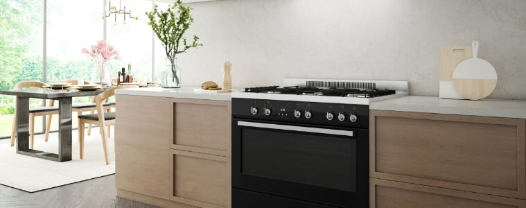 A black freestanding oven in a light timber and white kitchen.