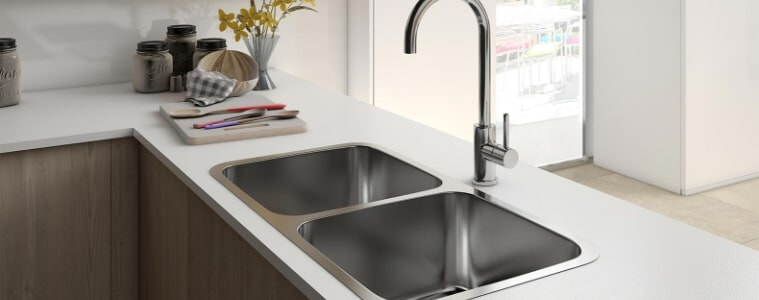 A chrome double kitchen sink on white a countertop.
