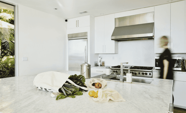 A white kitchen with fresh produce on the island.