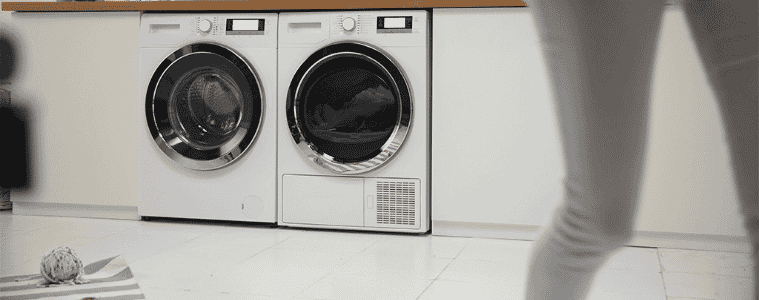 A person walks away from their side by side front loading washer and dryer.