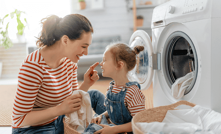 A woman does the washing with her young daughter.