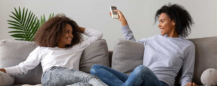 Two women relaxing on the couch whilst using their split system