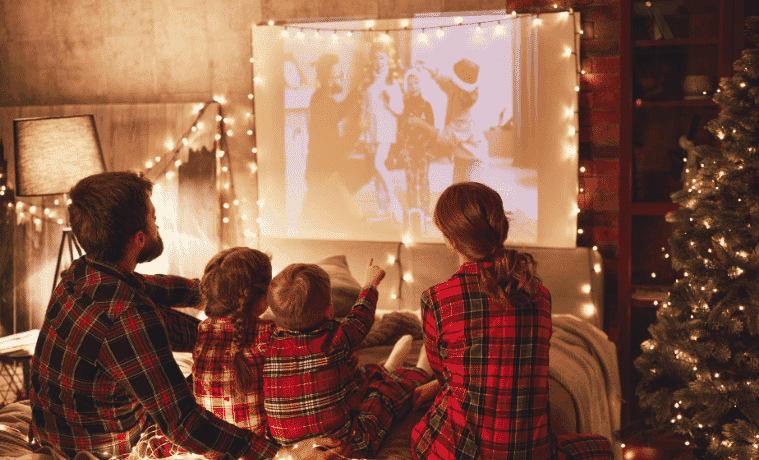 A young family watch a movie together on a projector.