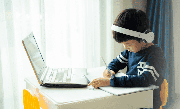 A child working on their laptop while using headphones