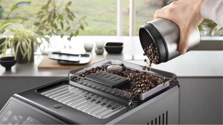 Man pouring coffee beans into the top of his De'Longhi Automatic Coffee Machine.