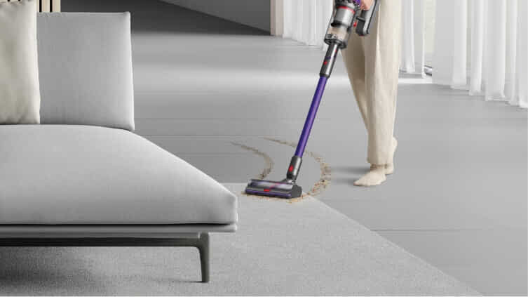 Woman changing from hard floor to carpet with her new dyson vacuum. 