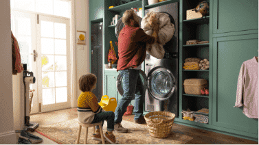 Man loading sheets into his LG WashTower  with his son.