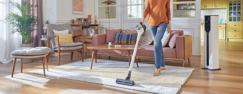 Woman using her LG CordZero A9T with the All-In-One station to easily clean her stylish home