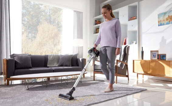 Woman using her LG Vacuum to clean dust of her rug in her living room