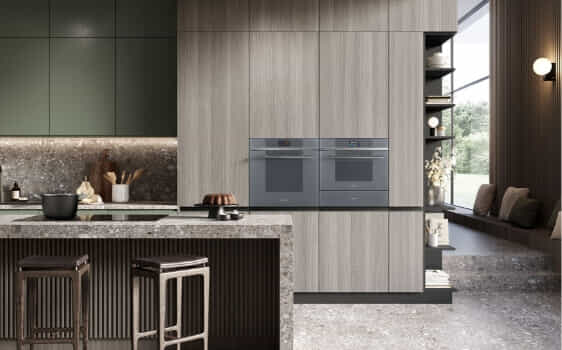 Two Smeg Linea ovens in a neutral and sage green kitchen.