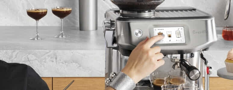 Woman using touch screen on breville coffee machine to make an espresso.